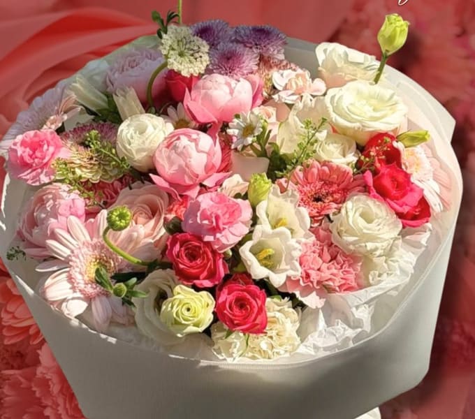Large pink and white bouquet of roses, lisianthus, and gerberas in white wrap